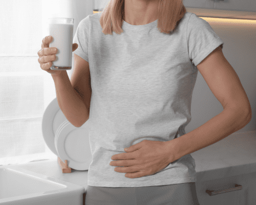 Mujer sosteniendo un vaso de leche con una mano y la otra apoyada en la barriga