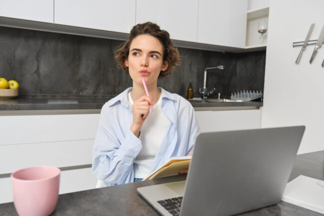 Young woman does homework, works from home, makes notes and uses laptop, managing business on remote, studies online Comparativa de ayunos por duración ¿Cuál es ideal para ti?